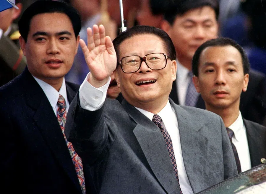 Chinese President Jiang Zemin smiles through the rain and waves to a crowd upon his arrival in Hong Kong on 30 June 1997.