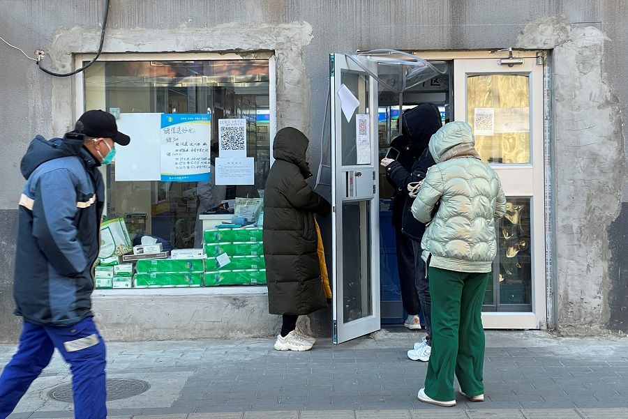 People wearing masks line up outside a pharmacy, as Covid-19 outbreaks continue, in Beijing, China, 13 December 2022. (Alessandro Diviggiano/Reuters)