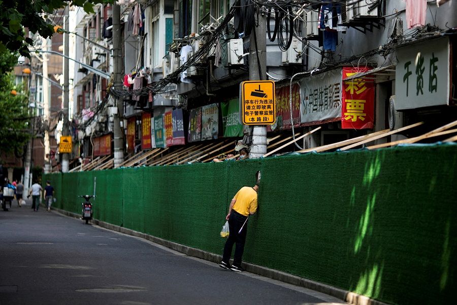 A man looks in through a gap in a barrier in a residential area, after the lockdown placed to curb the Covid-19 outbreak was lifted in Shanghai, China, 7 June 2022. (Aly Song/File Photo/Reuters)