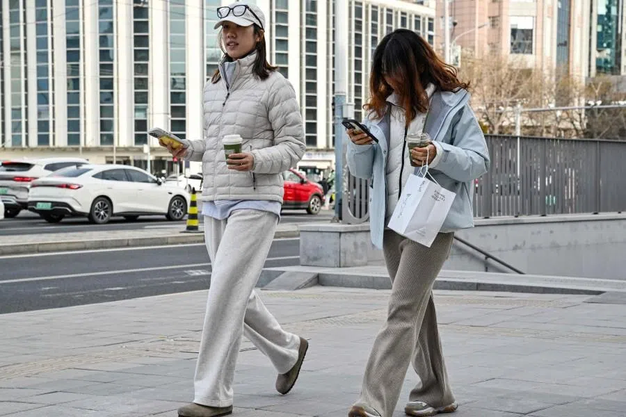 Two women walk along a street in Beijing on 4 January 2026. (Adek Berry/AFP)