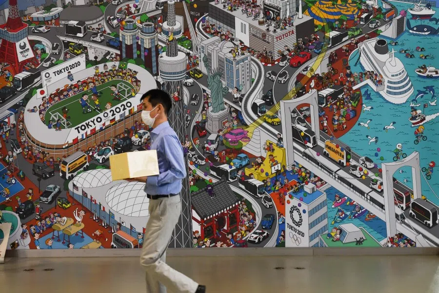 A man wearing a protective face mask walks past a mural inside Toyota's Mega Web showroom in Tokyo, 4 August 2020. (Noriko Hayashi/Bloomberg)