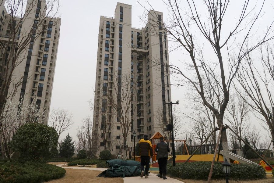 People walk inside the apartment compound Taoyuan Xindu Kongquecheng developed by China Fortune Land Development, in Zhuozhou, Hebei province, China, 19 March 2021. (Lusha Zhang/Reuters)