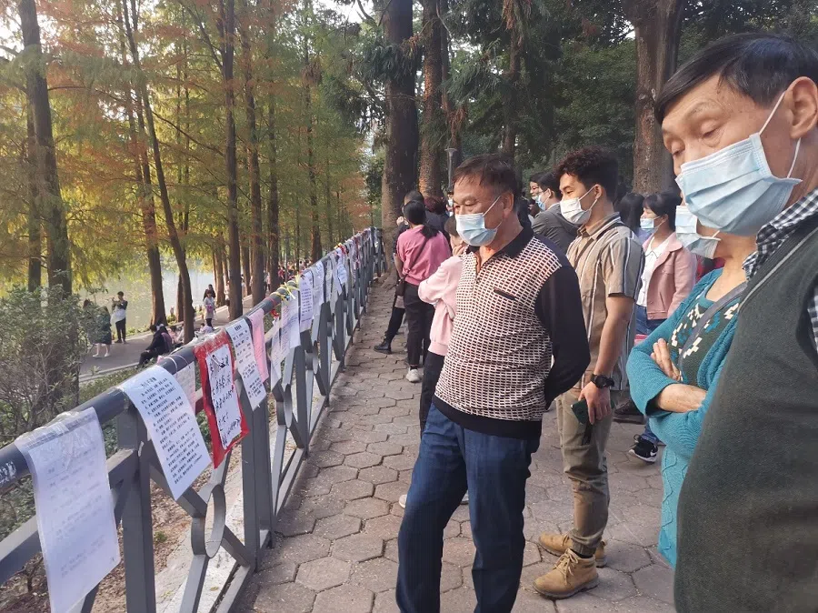 Elderly people look at posters with personal information at a matchmaking corner in Tianhe Park. (Photo: Zeng Shi)