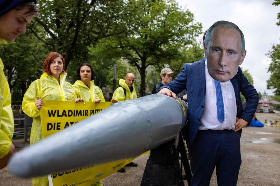 An activist wearing a mask of Russia's President Vladimir Putin stands next to fellow activists of the IPPNW (International Physicians for the Prevention of Nuclear War) peace organisation posing behind a mockup of a nuclear bomb as they demonstrate for the abolition of nuclear weapons in front of the Russian embassy in Berlin on 23 June 2023. (Odd Andersen/AFP)