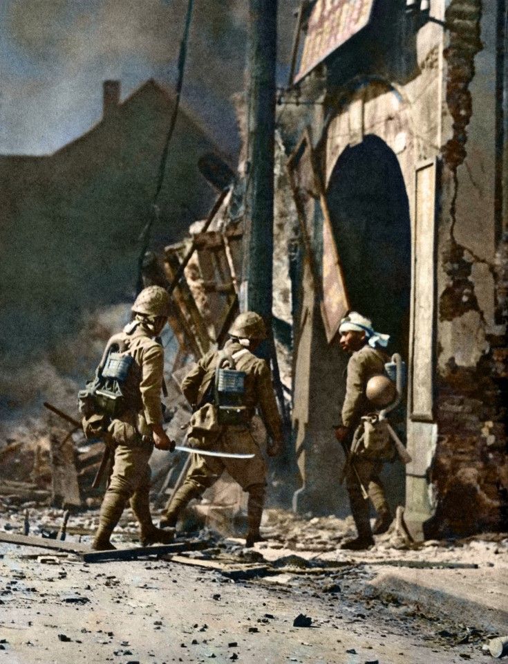 Japanese troops engaging in an intense street battle with Chinese troops in Zhabei, Shanghai, October 1937. The photo shows a Japanese soldier with a samurai sword drawn, ready to enter a home in search of anti-Japanese elements.