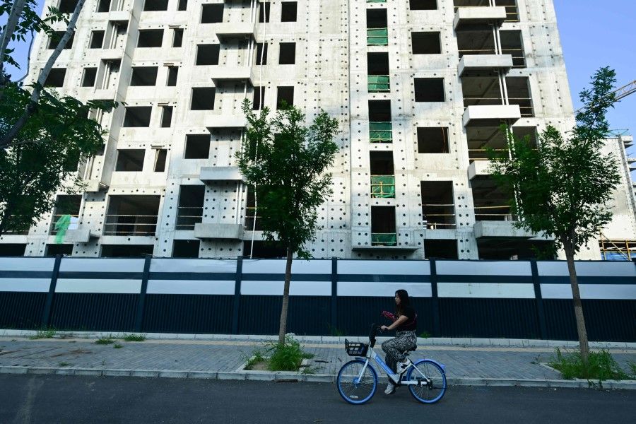 A woman rides past a development of property developer Country Garden in Beijing on 15 August 2023. Concerns are mounting in China around Country Garden, a major property developer whose colossal debt raises fear of a bankruptcy that could spell wider economic turbulence, two years after the unravelling of its competitor Evergrande. (Pedro Pardo/AFP)