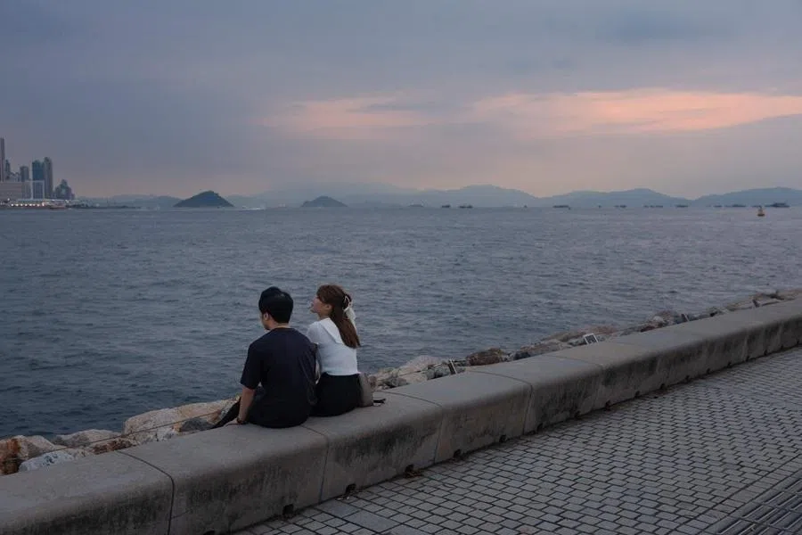 A couple relax on a promenade along Victoria Harbour in Hong Kong on 10 June 2026.