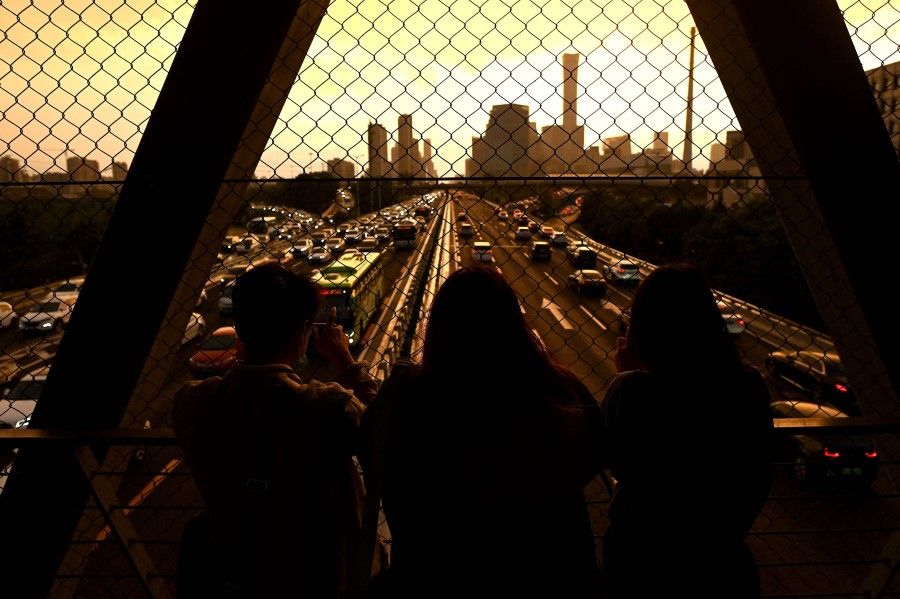 People take photos at an overpass overlooking the horizon as the sun sets in Beijing, China on 26 August 2021. (Noel Celis/AFP)