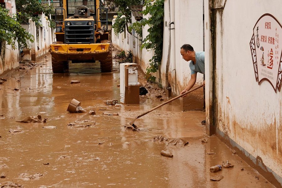 This photo taken on 16 July 2022 shows a man clearing a residential area after flooding in Longnan, Gansu province, China. (AFP)