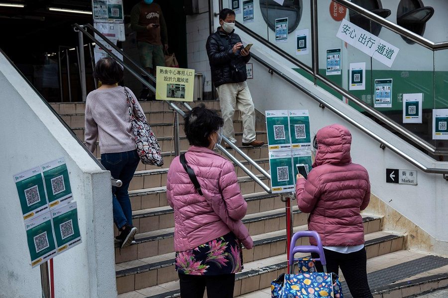 People scan a QR code before entering a wet market in Hong Kong on 3 March 2022. (Isaac Lawrence/AFP)