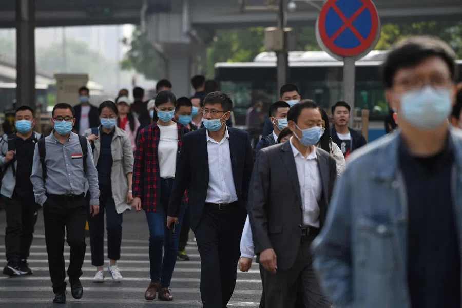 Commuters cross a street during the morning rush hour in Beijing, China on 11 May 2021. (Greg Baker/AFP)