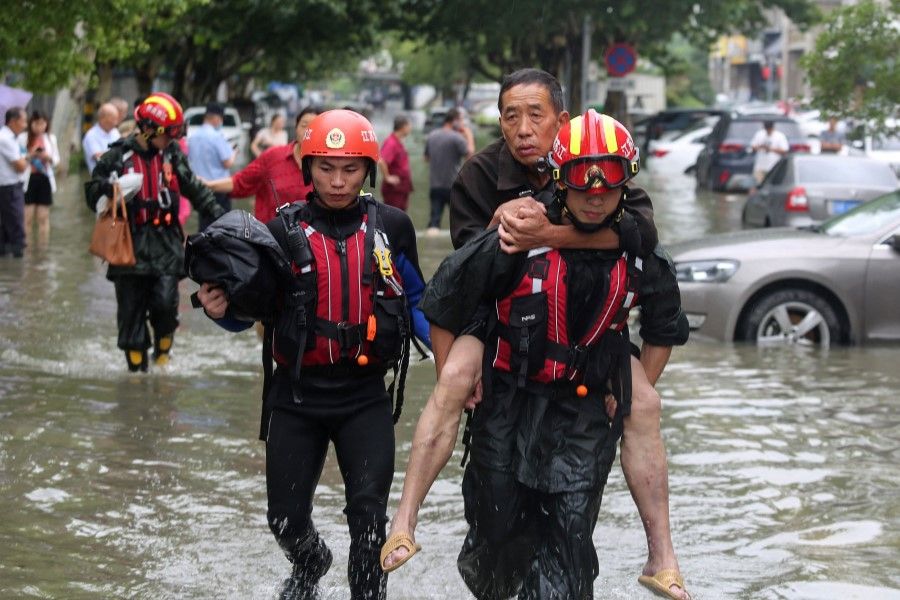 This photo taken on 28 July 2021 shows rescuers evacuating residents at a flooded area in Yangzhou, in China's eastern Jiangsu province, after heavy rains brought by the passage of Typhoon In-Fa inundated the eastern coast of China. (STR/AFP)
