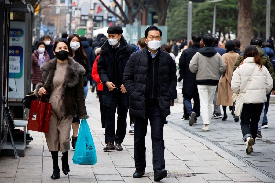 People wearing masks to prevent contracting the coronavirus disease (Covid-19) walk on a street in downtown Seoul, South Korea, 5 January 2022. (Heo Ran/Reuters)