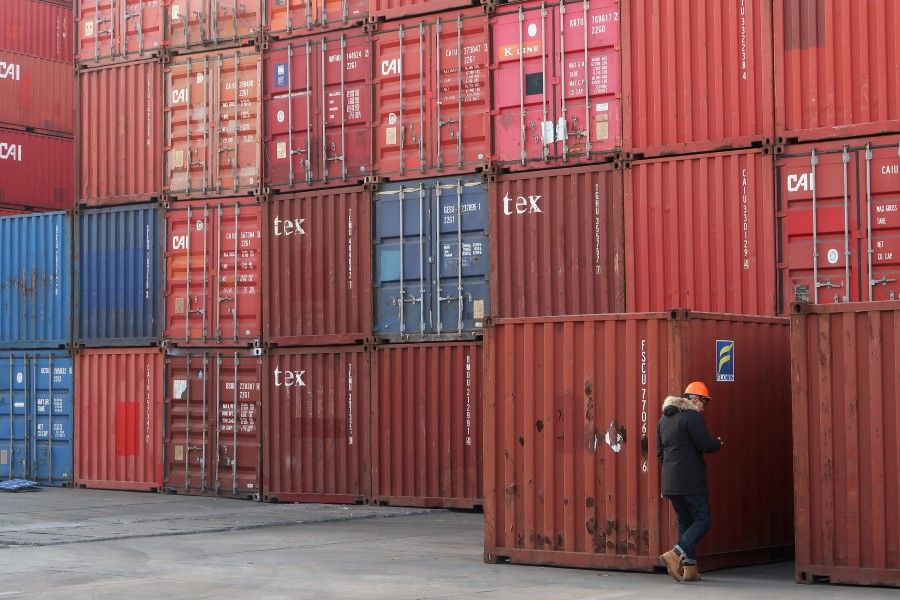 A worker checks containers at a logistics center near Tianjin port, in Tianjin, 12 December 2019. (Yilei Sun/REUTERS)