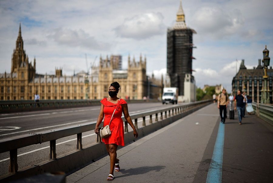 A pedestrian wearing a face mask walks over Westminster Bridge near the Houses of Parliament in central London on 7 June 2021. (Tolga Akmen/AFP)