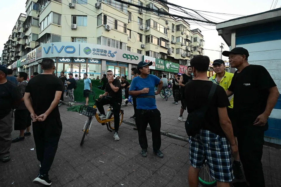 Men gather at a labour market in Beijing on 15 August 2023, where people are hired for temporary jobs at factories and construction sites. (Pedro Pardo/AFP)