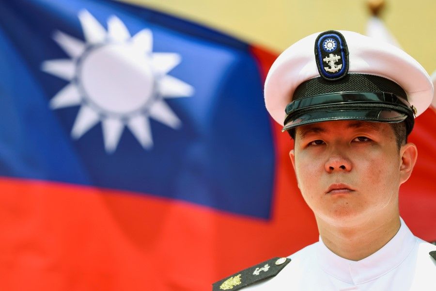 A Taiwan Navy honour guard looks on in front of a Taiwan flag during the launch ceremony for the Taiwan Navy's domestically built amphibious transport dock "Yushan" in Kaohsiung, Taiwan, 13 April 2021. (Ann Wang/Reuters)