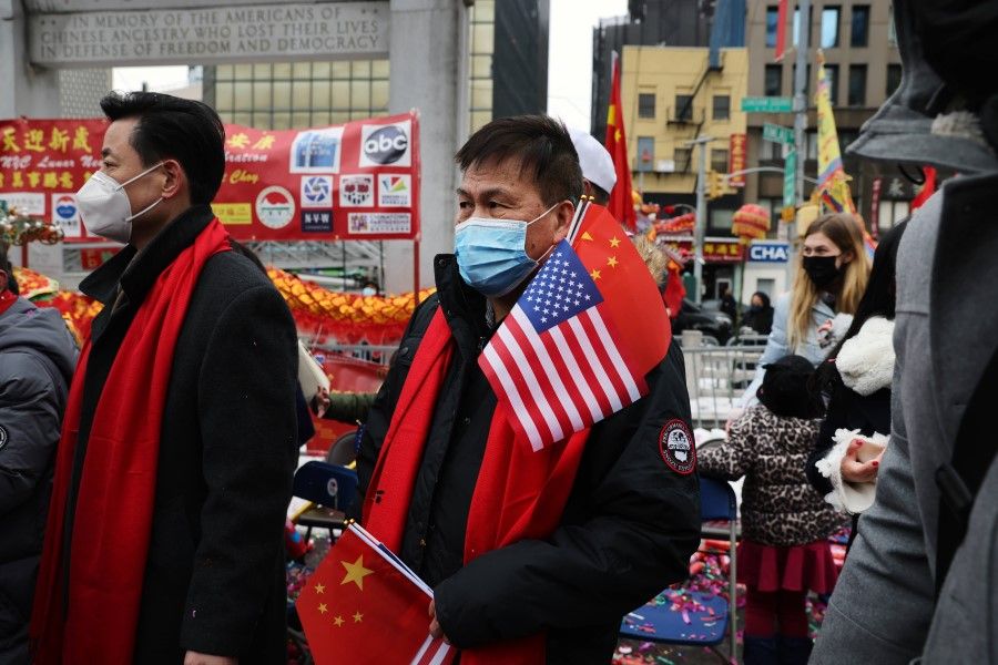 A man holds the US and China flags in a Lunar New Year ceremony in Chinatown on 12 February 2021 in New York City. (Spencer Platt/AFP)
