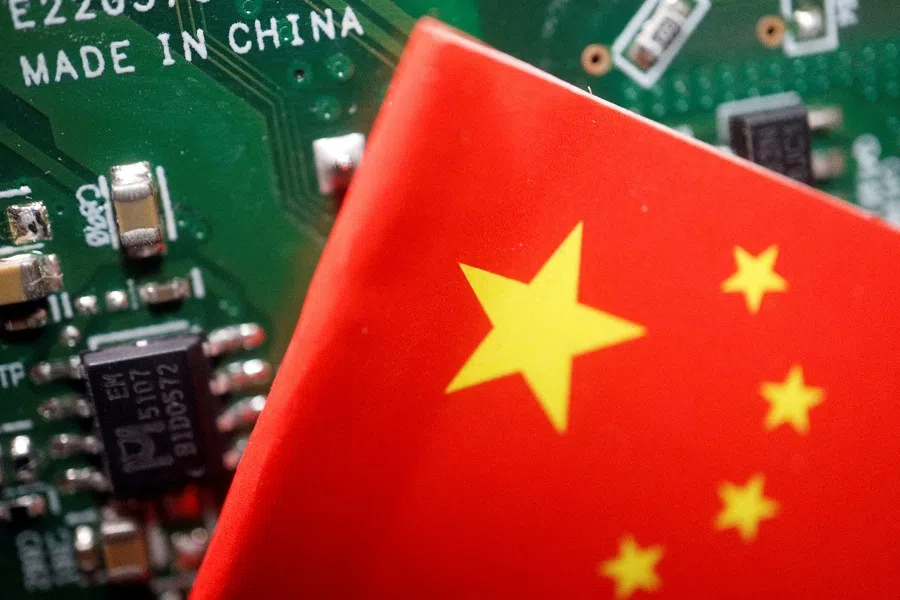 A Chinese flag is displayed next to a "Made in China" sign seen on a printed circuit board with semiconductor chips, in this illustration picture taken 17 February 2023. (Florence Lo/Illustration/File Photo/Reuters)