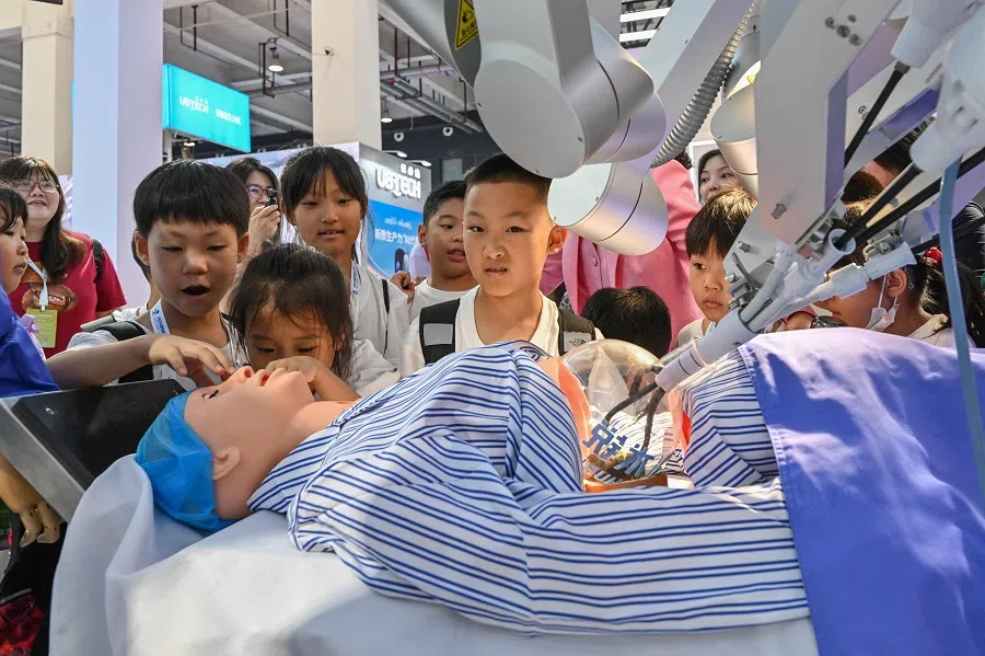 School children check a robot used during surgery at the World Robot Conference in Beijing, China, on 21 August 2024. (Adek Berry/AFP)