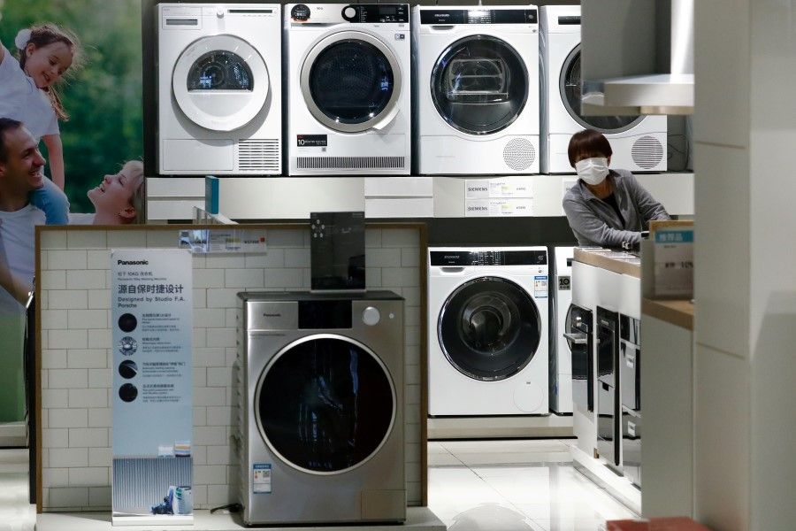 A woman wearing a protective mask looks at products at a home appliances retailer, following the Covid-19 outbreak, in Beijing, China, on 25 March 2020. (Thomas Peter/File Photo/Reuters)