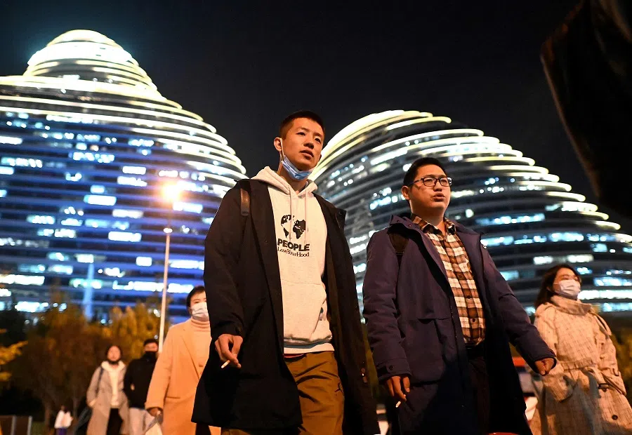 People cross a street in Beijing, China, on 20 October 2021. (Noel Celis/AFP)