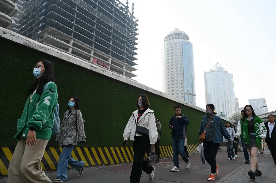 People walk past buildings in Beijing’s central business district as they walk to work on 11 April 2025. (Greg Baker/AFP)