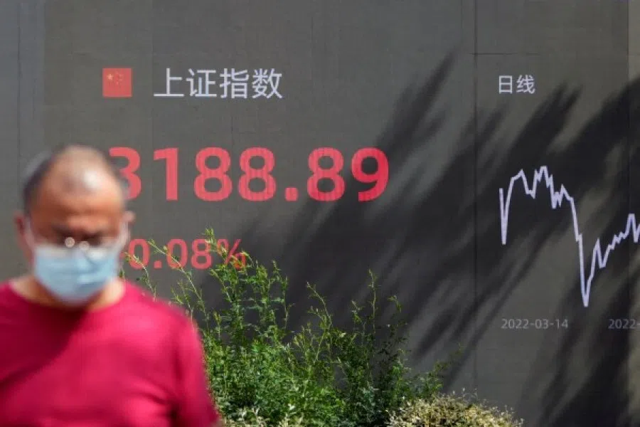 A pedestrian walks past a giant display showing the Shanghai stock index, in Shanghai, China, 3 August 2022. (Reuters/Aly Song)