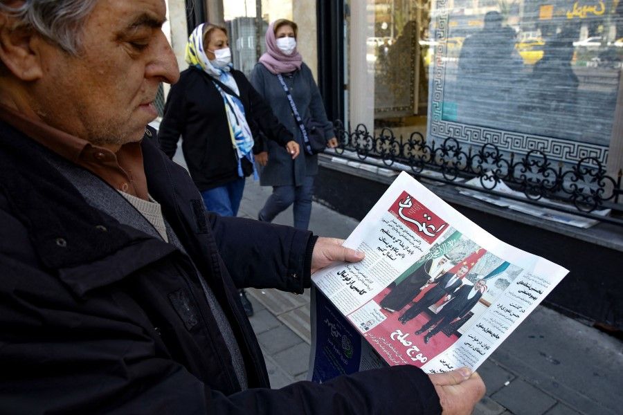 A man in Tehran holds a local newspaper reporting on its front page the China-brokered deal between Iran and Saudi Arabia to restore ties, signed in Beijing the previous day, on 11 March 2023. (Atta Kenare/AFP)