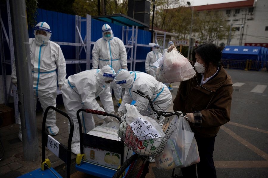 A woman delivers food to a residential compound that is under lockdown as Covid-19 outbreaks continue in Beijing, China, on 28 November 2022. (Thomas Peter/Reuters)