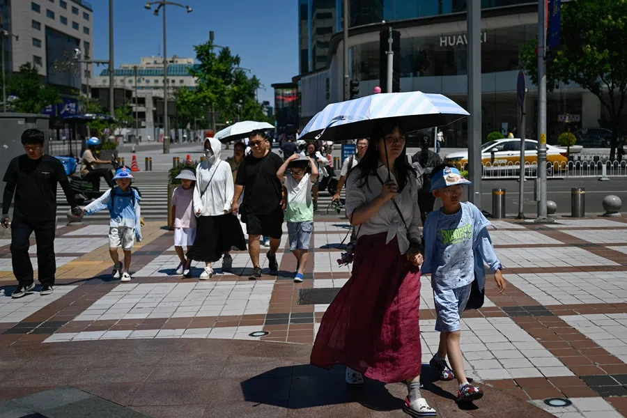 People walk down a street at a business district in Beijing on 17 July 2025. (Wang Zhao/AFP)