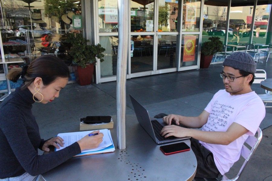 Two Chinese students from Stanford University study together at a sidewalk table in the Silicon Valley city of Palo Alto on March 12, 2020. (Glenn Chapman/AFP)
