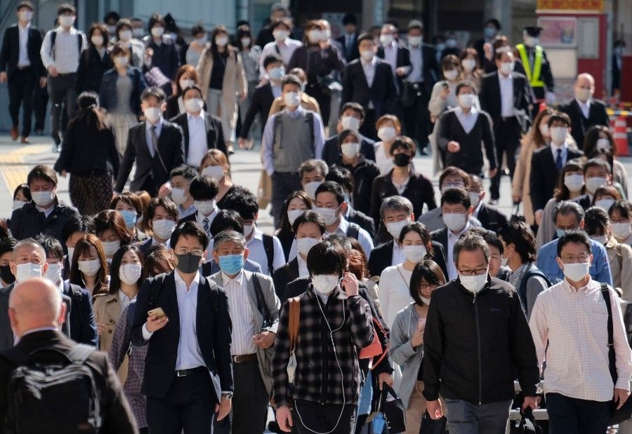 Commuters wearing face masks cross a street by a railway station in Tokyo, 7 May 2020. (Kazuhiro Nogi/AFP)