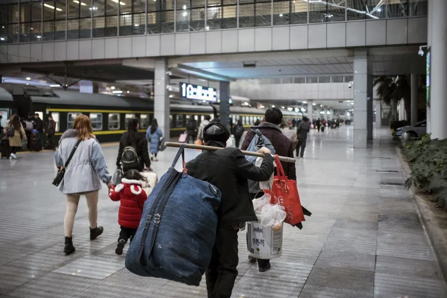 A man totes his belongings on a pole in Shanghai Railway Station, 17 January 2020. (Qilai Shen/Bloomberg)