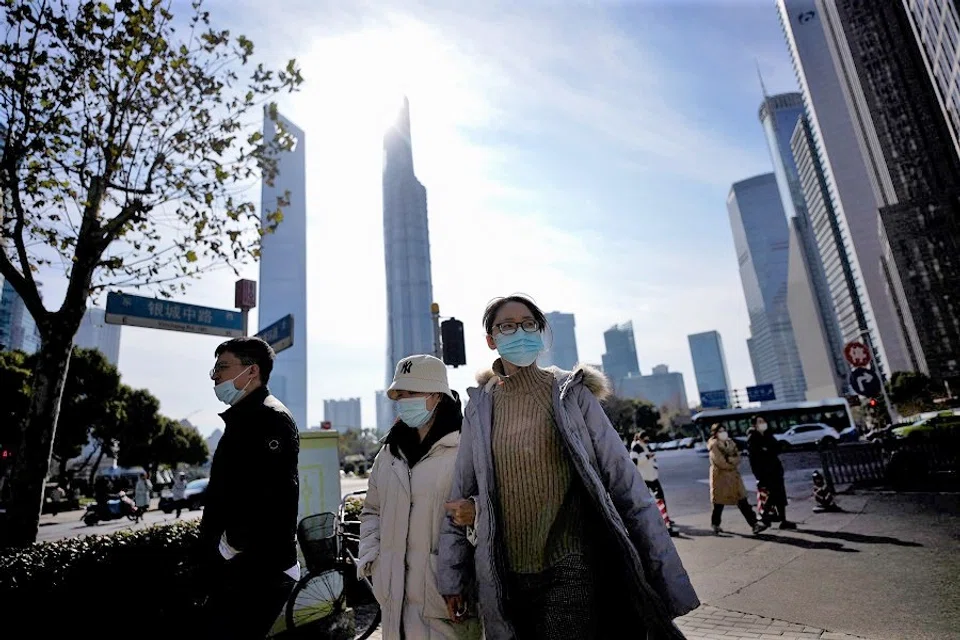 People wearing protective masks walk on a street in Shanghai, China, 14 January 2022. (Aly Song/Reuters)