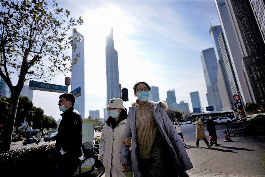 People wearing protective masks walk on a street in Shanghai, China, 14 January 2022. (Aly Song/Reuters)