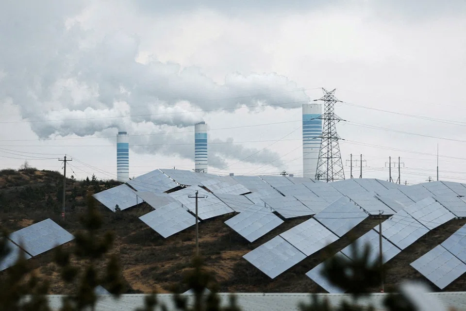 Smoke rises from chimneys near solar panels in Shaanxi province, China, 24 April 2023. (Tingshu Wang/File Photo/Reuters)