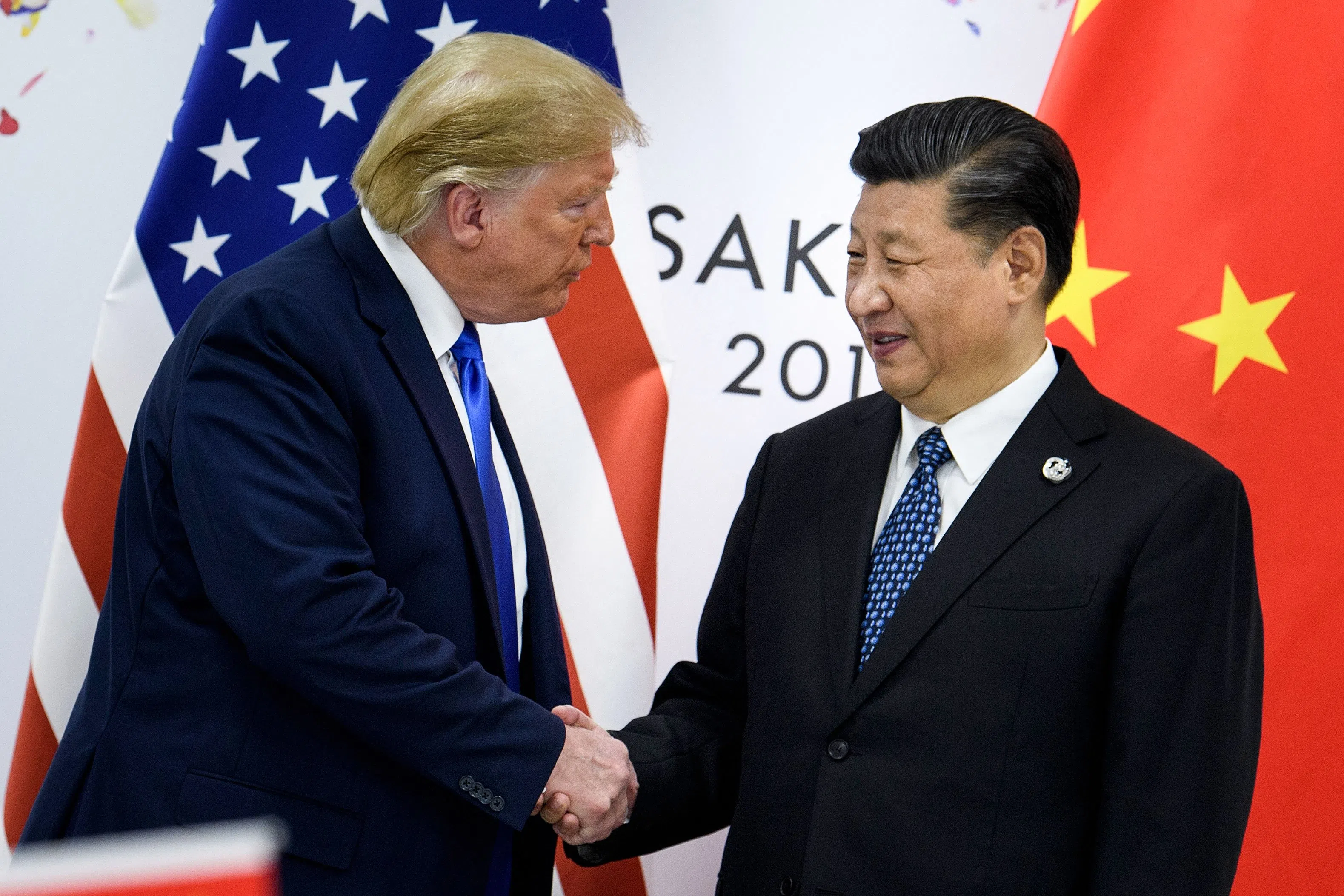 This file photo taken on 28 June 2019 shows China’s President Xi Jinping shaking hands with US President Donald Trump before a bilateral meeting on the sidelines of the G20 summit in Osaka. (Brendan Smialowski/AFP)