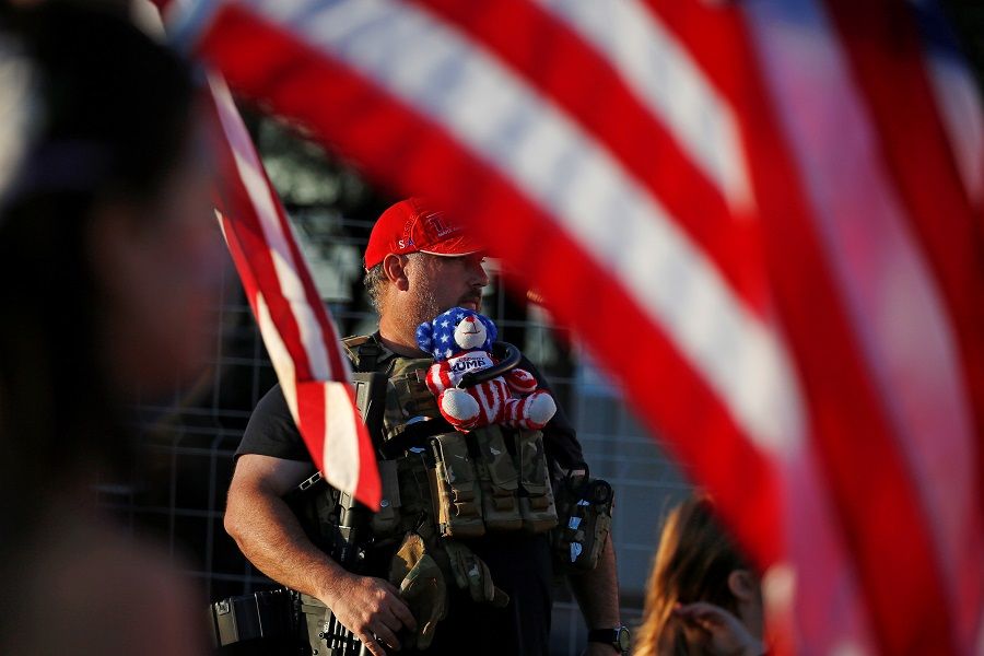A supporter of US President Donald Trump carries a teddy bear and a semi-automatic rifle at a "Stop the Steal" protest after the 2020 US presidential election was called for Democratic candidate Joe Biden, at the Maricopa County Tabulation and Election Center (MCTEC), in Phoenix, Arizona, US, 9 November 2020. (Jim Urquhart/Reuters)