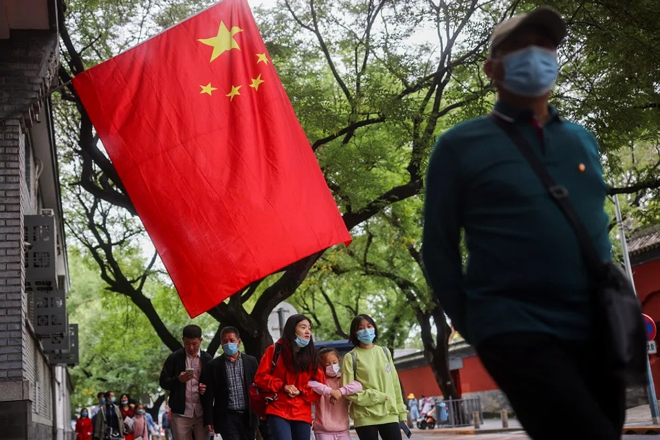 People walk past a Chinese flag near the Forbidden City during National Day holidays in Beijing, China, 5 October 2021. (Thomas Peter/Reuters)