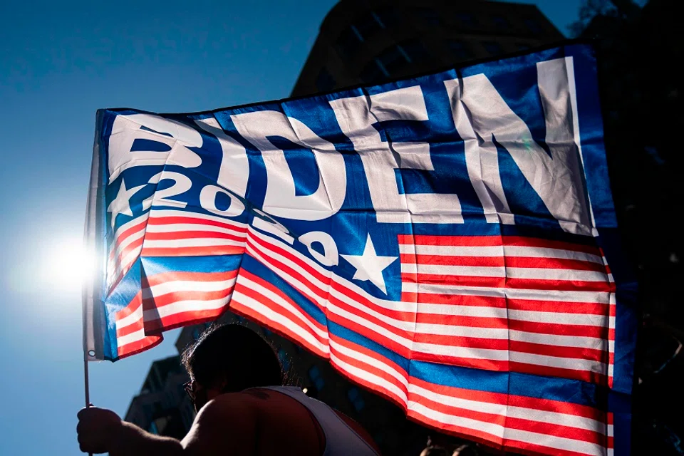 A supporter of US President-elect Joe Biden waves a flag as people celebrate on Black Lives Matter plaza across from the White House in Washington, DC on 7 November 2020. (Alex Edelman/AFP)