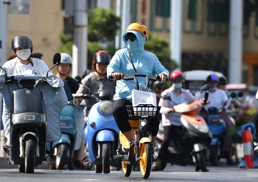 People ride vehicles on a street amid a heatwave warning in Fuyang, Anhui province, China, 13 August 2022. (CNS photo via Reuters)