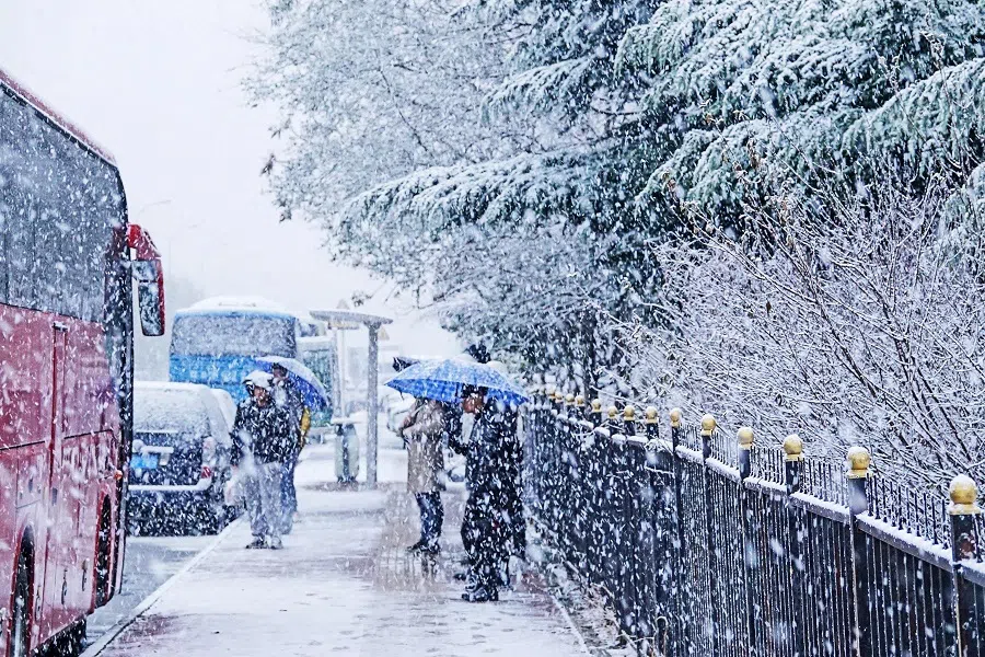 Commuters wait for transport at a bus station during snowfall in Dalian, in China's northeastern Liaoning province on 23 November 2023. (AFP)