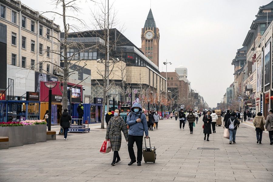 Pedestrians wearing protective masks walk past stores in the Wangfujing shopping area of Beijing, China, on 5 March 2021. (Qilai Shen/Bloomberg)