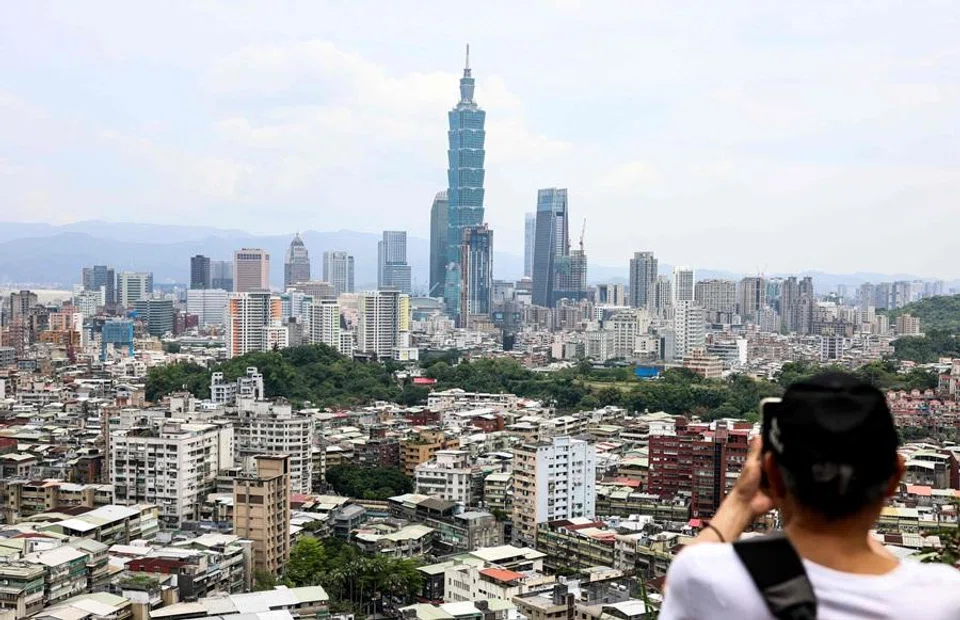 A man takes photos of the Taipei 101 building standing among residential and commercial buildings in Taipei on 28 April 2026. (I-Hwa Cheng/AFP)