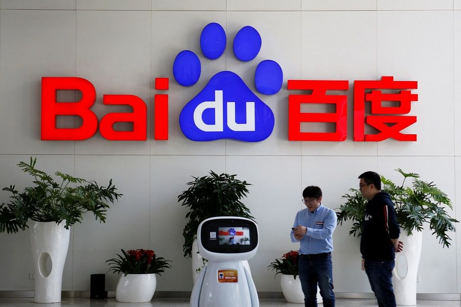 Men interact with a Baidu AI robot near the company logo at its headquarters in Beijing, China, 23 April 2021. (Florence Lo/File Photo/Reuters)