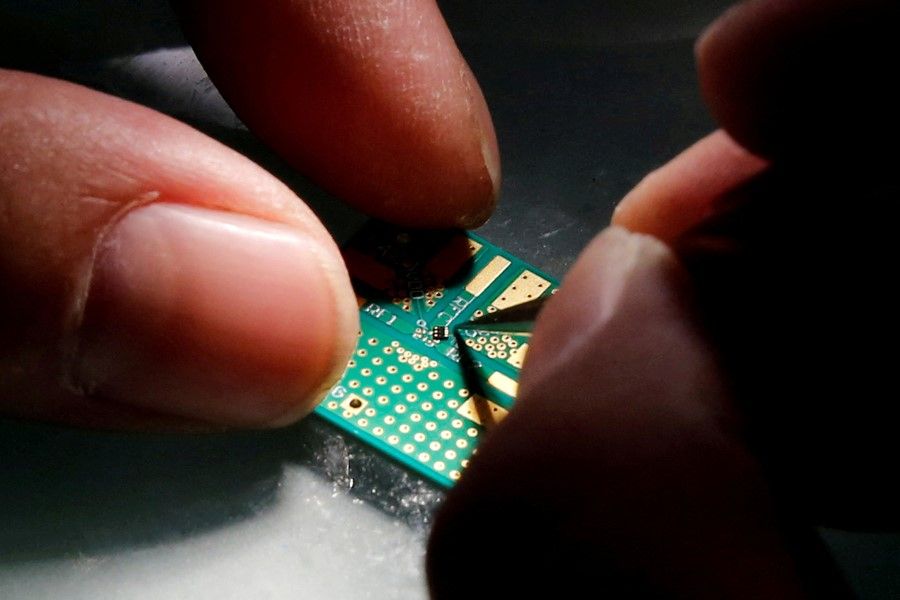 A researcher plants a semiconductor on an interface board during a research work to design and develop a semiconductor product at Tsinghua Unigroup research centre in Beijing, China, 29 February 2016. (Kim Kyung-Hoon/Reuters)