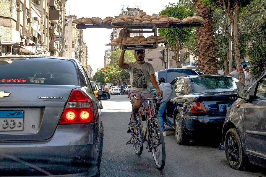 A deliveryman rides his bicycle through traffic in central Cairo, Egypt, on 17 May 2024. (Amir Makar/AFP)
