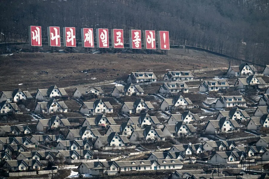 This picture taken on 29 February 2024 shows the North Korean town of Chunggang with a sign reading “My country is the best” as seen from the vicinity of the Chinese border town of Linjiang in China’s northeast Jilin province. (Pedro Pardo/AFP)