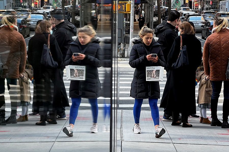 People are reflected in a window as they walk though the Manhattan borough of New York City, New York, US, 26 February 2022. (Carlo Allegri/Reuters)